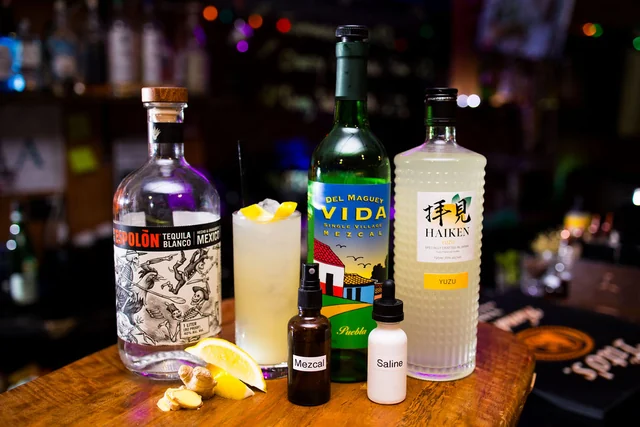 Espolòn, Del Maguey Vida and a bottle of yuzu beside a pale cocktail.