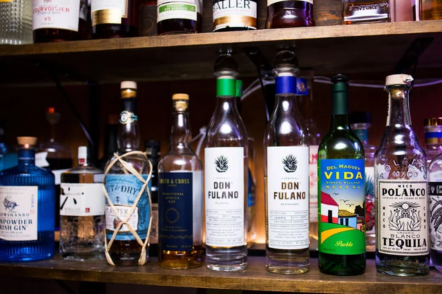 A row of tequila and mezcal bottles behind the bar.