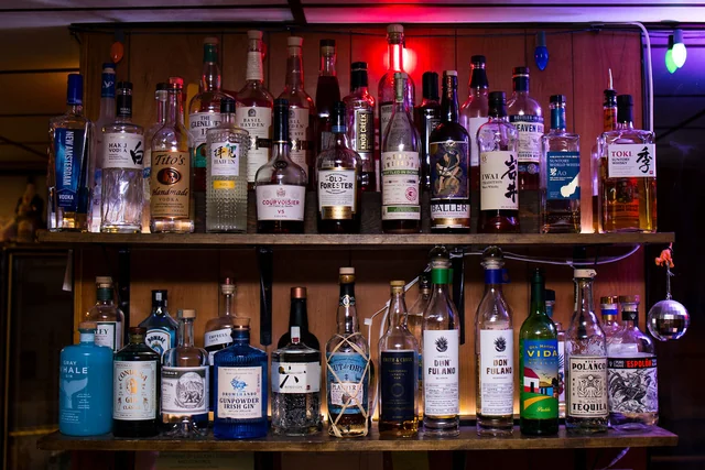 Two rows of spirits beneath colored string lights behind the bar.