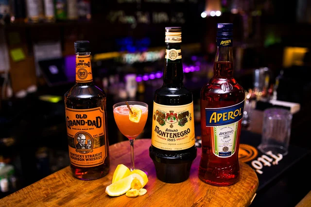 Old Grand-Dad, Amaro Montenegro and Aperol beside an orange cocktail.