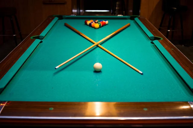 Easy Tiger’s green pool table with crossed cues and a rack of balls.