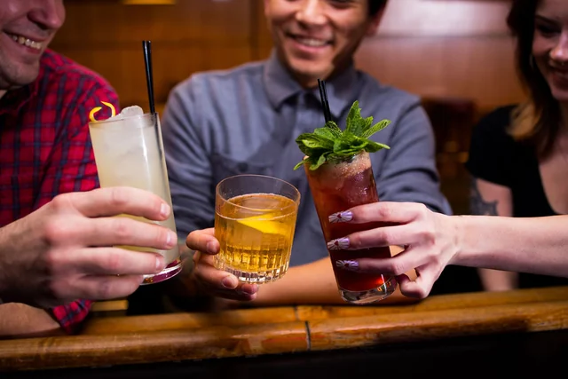 Three people raise different cocktails together at Easy Tiger.